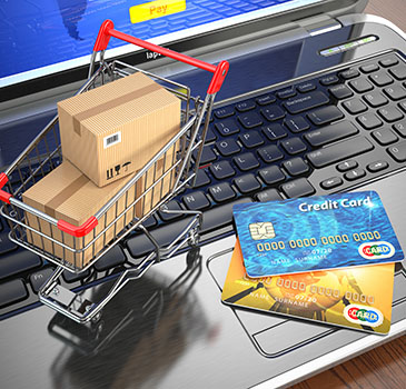 E-commerce. Shopping cart and credit cards on laptop. 3d